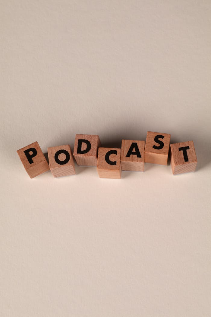 Wooden letter blocks arranged to spell 'Podcast' on a smooth beige background.