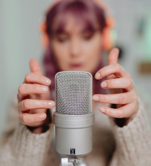 Close-up of a woman recording ASMR with a microphone indoors.